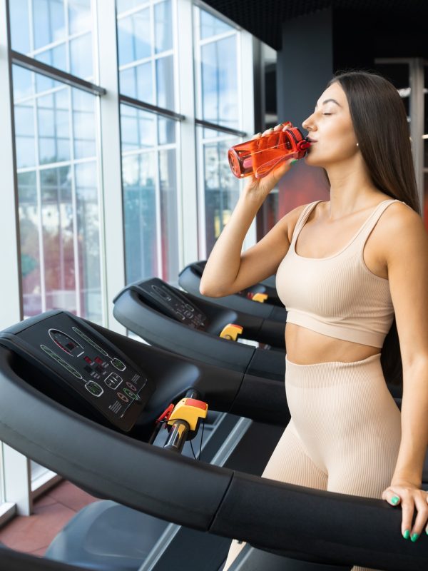 Slender woman on a treadmill drinking water